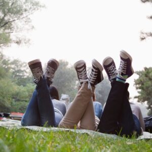 Photo des jambes de trois ado étendus sur une couverture dans l'herbe.